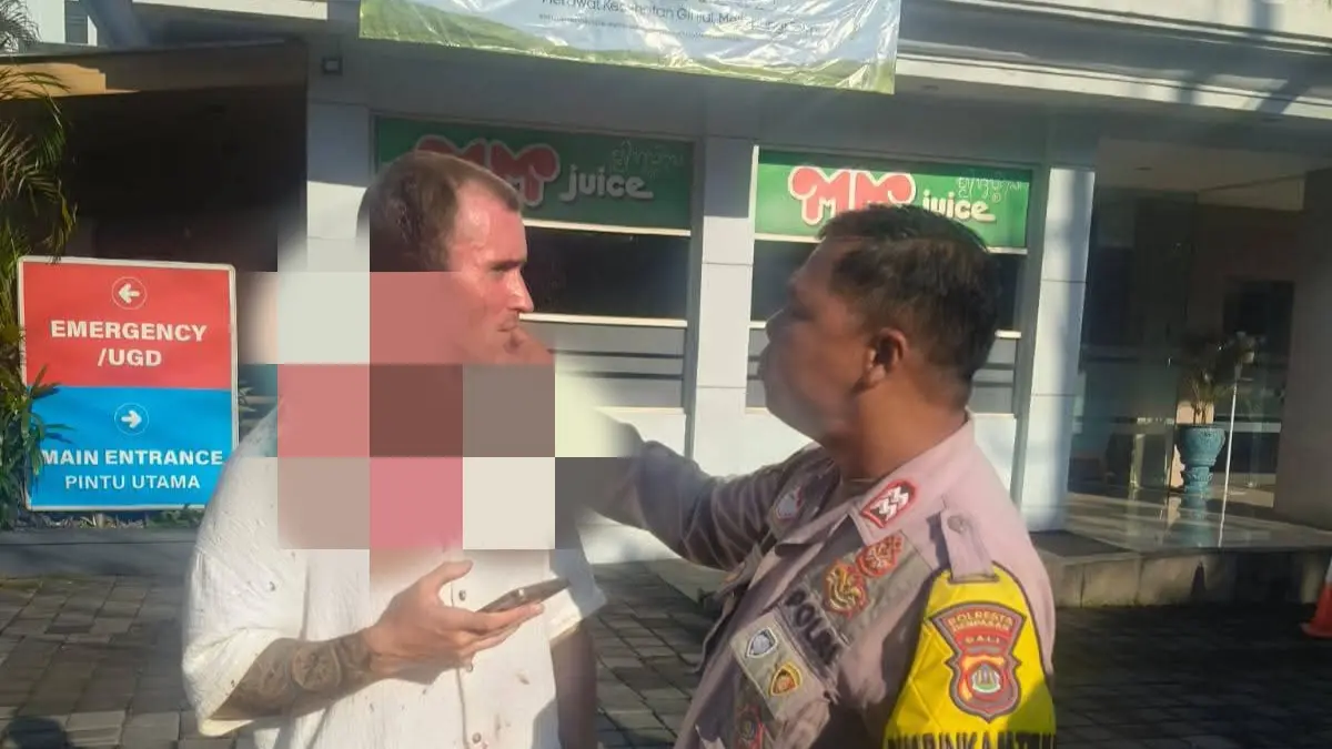 Seorang anggota kepolisian menenangkan pelaku WNA yang diduga melakukan penganiayaan di IOWA Gym, Jalan Pura Demak I, Denpasar Barat, Rabu (15/4/2026), sebelum diamankan untuk menjalani pemeriksaan lebih lanjut. (Fot Polresta Denpasar) 