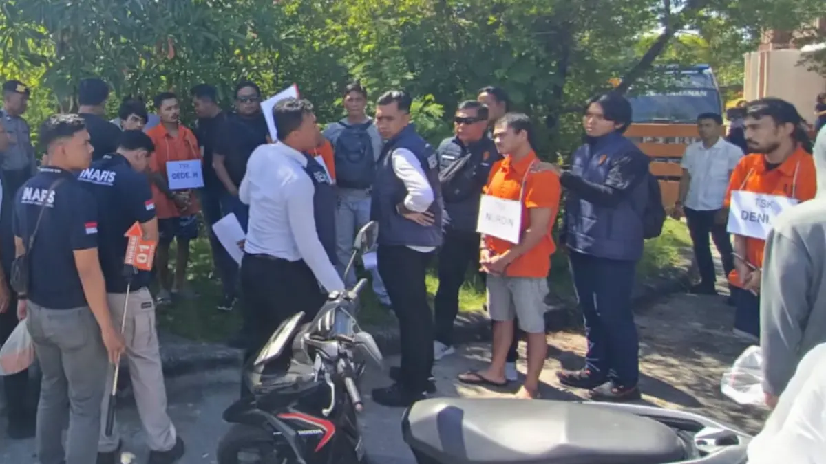 Petugas kepolisian membawa tersangka ke lokasi kejadian saat proses rekonstruksi kasus pembakaran jenazah di kawasan Pelabuhan Benoa.(Foto Adrian Suwanto) 