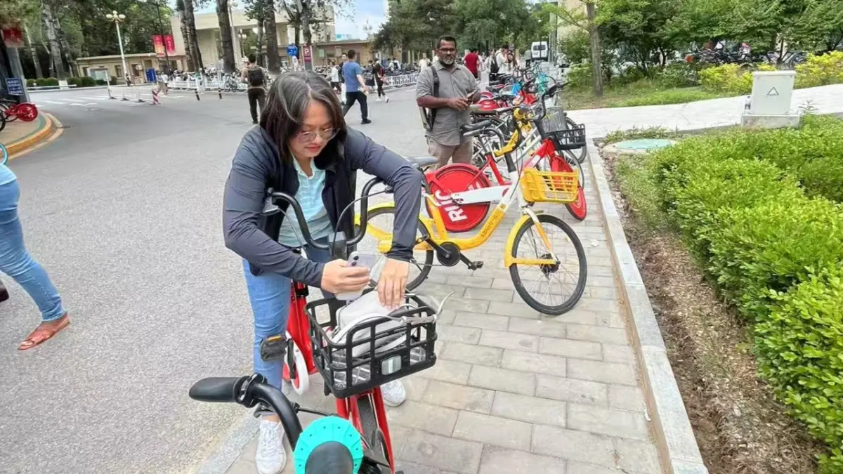Janelle Lorenzo, jurnalis asal Filipina peserta CIPCC mencoba layanan sepeda bike sharing di Renmin University of China. Layanan ini populer karena murah dan mudah diakses. (Foto Eka Prasetya) 