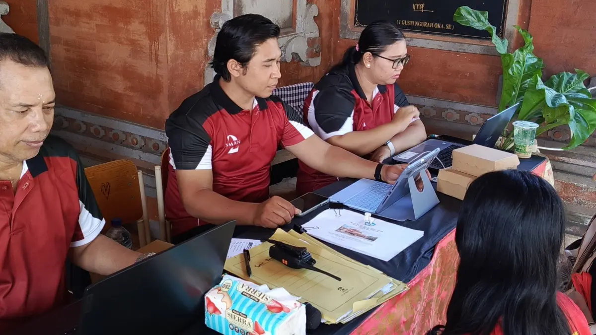 Petugas memeriksa dan memverifikasi berkas calon siswa baru pada proses SPMB Tahun Ajaran 2026/2027 di posko layanan SMA Negeri 2 Denpasar. Antusiasme pendaftar terlihat tinggi sejak hari pertama pembukaan. (Foto I Wayan Widyantara) 