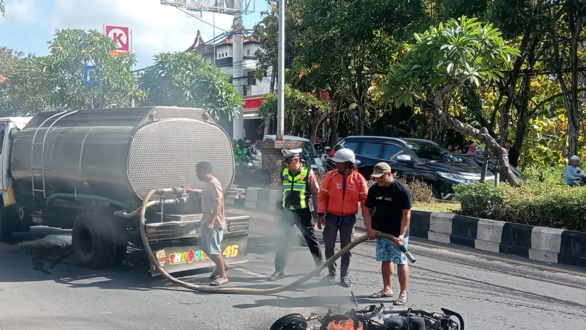 Petugas kepolisian bersama warga berupaya memadamkan kobaran api yang melalap sepeda motor usai mengalami kecelakaan tunggal di Jalan Bypass Ngurah Rai, tepatnya depan Bengkel Athena Motor, Lingkungan Mumbul, Kuta Selatan, Badung, Senin (13/7) kemarin. (Foto: Adrian Suwanto) 