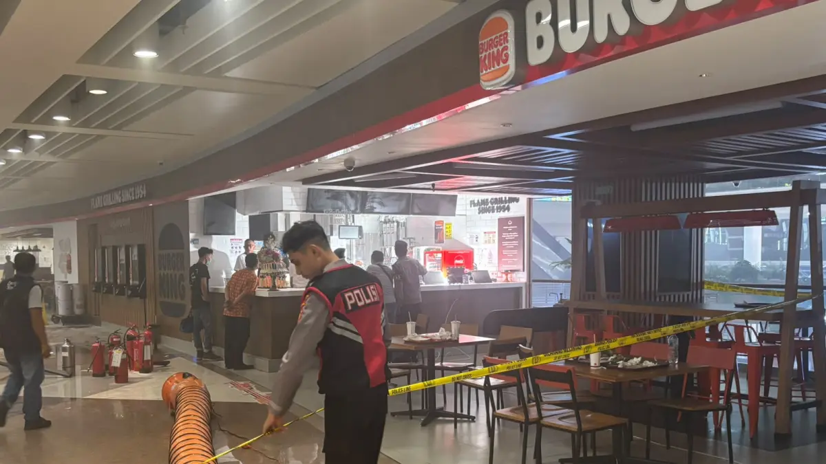 Personel Polres Kawasan Bandara I Gusti Ngurah Rai memasang garis polisi di tenant Burger King lantai 2 Terminal Internasional Bandara I Gusti Ngurah Rai usai kebakaran, Kamis (30/7) malam. (Istimewa)