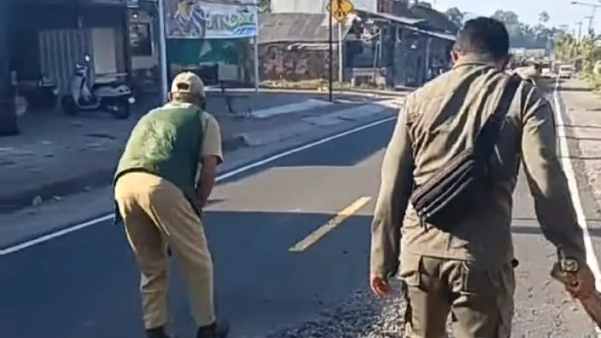 Petugas Forkompincam Kecamatan Rendang membersihkan sisa ceceran material galian C yang tercecer di jalur utama Rendang, Karangasem.(Foto Camat Rendang)