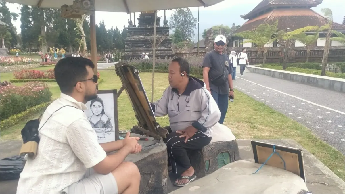 Putu Budi saat melukis wajah wisatawan di kawasan DTW Taman Danu Beratan, Bedugul, Tabanan. (Juliadi)