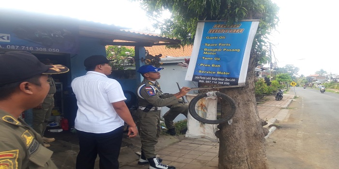 Petugas melakukan penertiban pedagang yang jualan di trotoar dan banner iklan yang dipaku pada pohon.