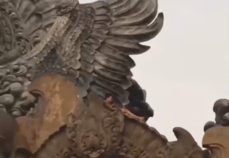 SAMAR-SAMAR: Seorang remaja sedang duduk santai di kepak sayap patung Garuda Wisnu Serasi Tabanan   akhirnya diamankan Satpol PP Tabanan