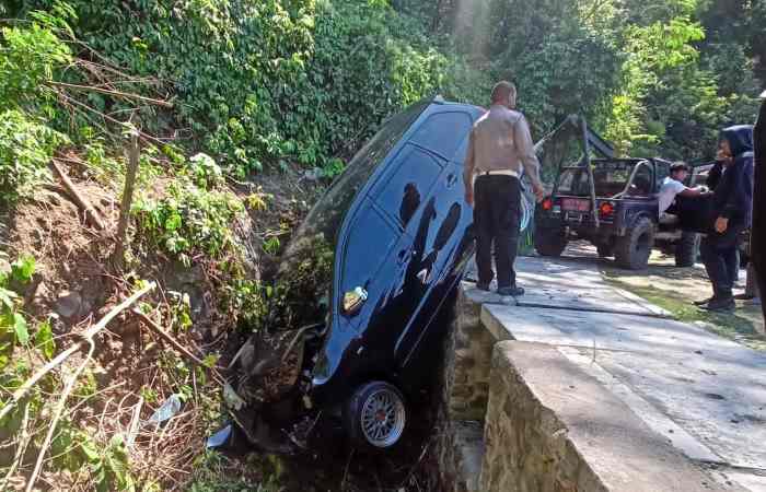 DIVAKUASI : Petugas saat melakukan evakuasi terhadap mobil Avanza yang dikemudikan I Dewa Agung Tresna Yoga usai nyemplung ke got di Jalan Raya Sang Hyang Ambu, Karangasem.
