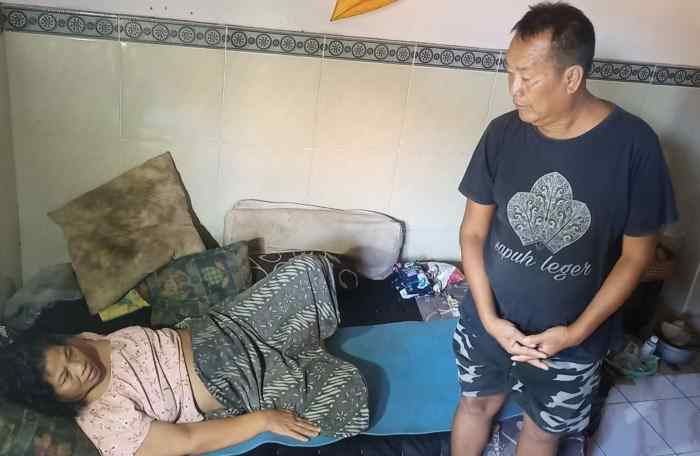 NESTAPA YANG BUTUH KESABARAN EKSTRA: Ni Nyoman Suki ditemani sang suami I Ketut Merta hanya bisa berbaring di ranjang dengan kondisi mengidap kanker rahim sejak 4,5 tahun lalu.