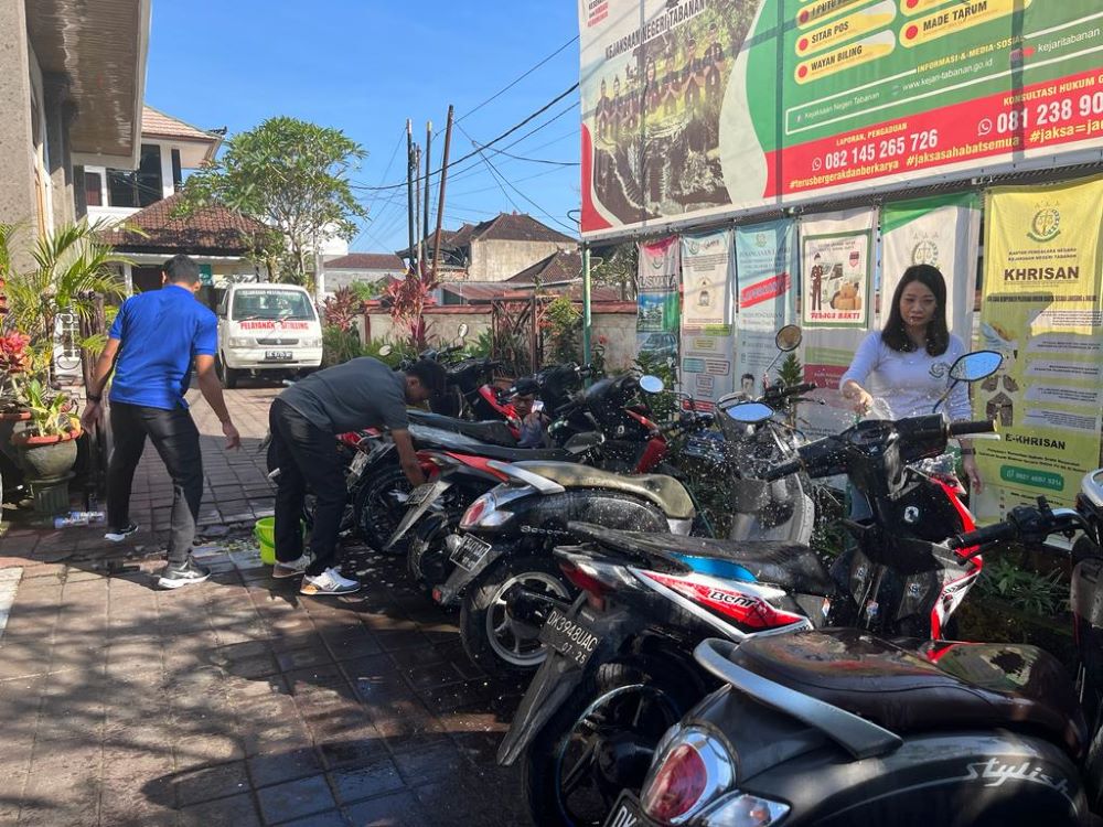 KERJA BAKTI: pegawai dan staf dari PB3R Kejari Tabanan yang mencuci barang bukti sepeda motor di halaman Kantor Kejari Tabanan .