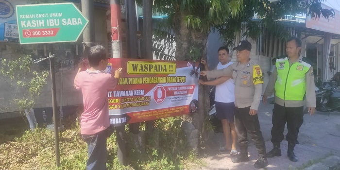Polisi memasang spanduk himbauan terhadap tindak pidana perdagangan orang.