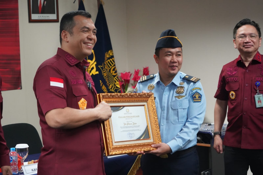 PRESTASI: Dirjen Imigrasi Silmy Karim (kiri) menyerahkan penghargaan kepada 16 petugas imigrasi yang berhasil meringkus buronan interpol asal Kanada berinisial SG, 50, Minggu (1/7/2023). (RADAR BALI