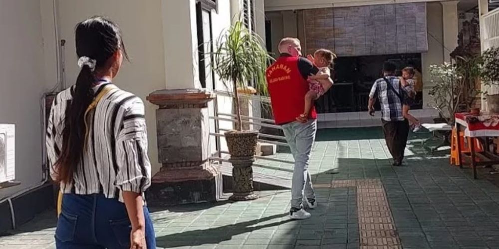 HUKUMAN RINGAN: Terdakwa Stephen Michael Jamnitzky menggendong anaknya sebelum menjalani sidang putusan di PN Denpasar, Selasa 4 Juli 2023.