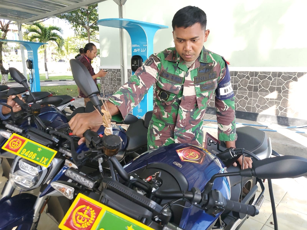 RESPONS CEPAT: Adam Prawira, Komandan Kompi A Raider 900 memastikan kesuksesan proses pengisian ulang daya pada motor listrik, Kamis (13/7/2023). (RADAR BALI PHOTO)