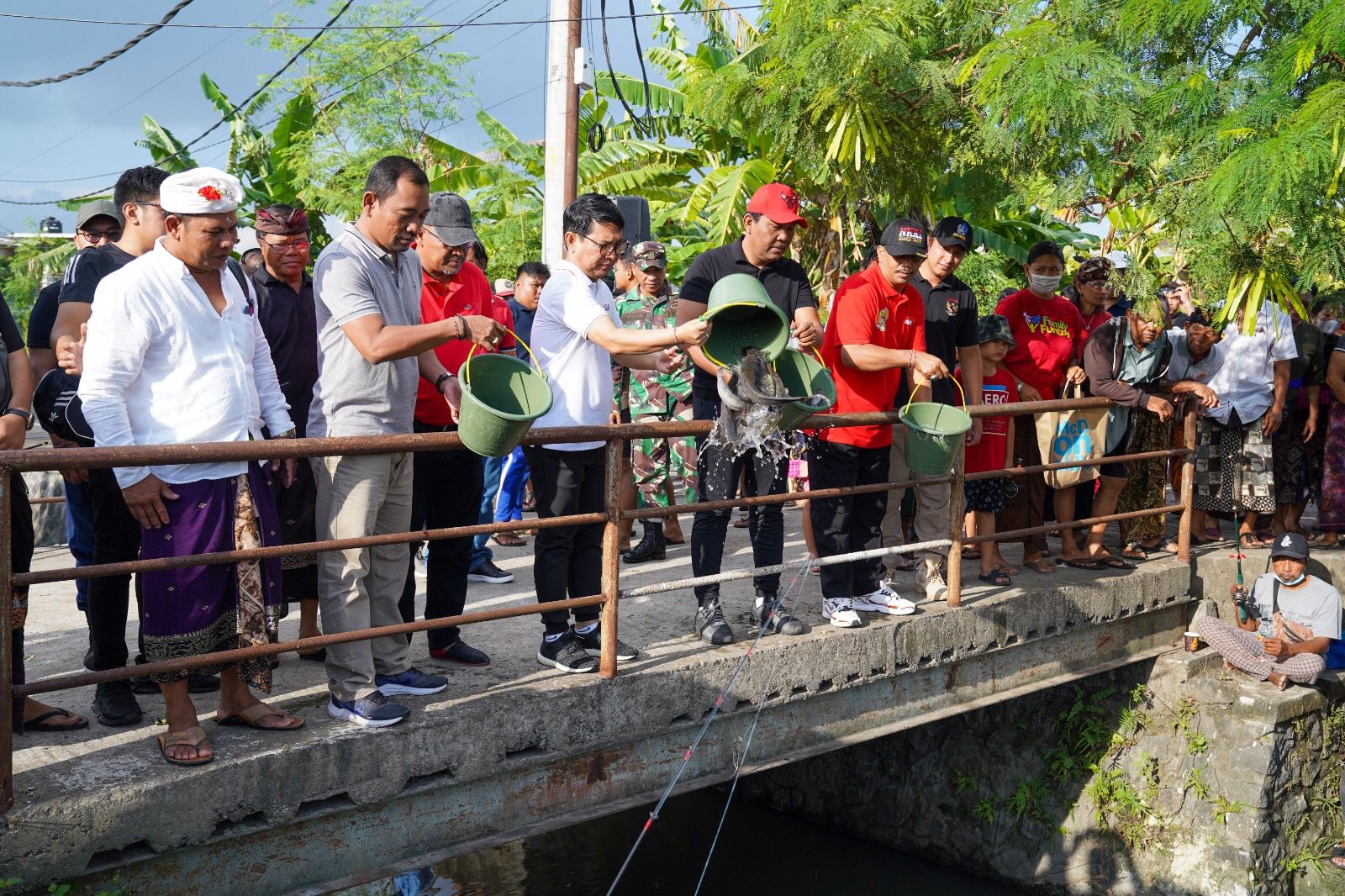 TABUR LELE: Sekda I Wayan Adi Arnawa saat membuka lomba mancing air deras yang ditandai dengan menabur ikan lele, di Saluran Sungai Anak Tukad Mati Tatag,  Seminyak, Minggu (16/7/2023). (Humas Badung)
