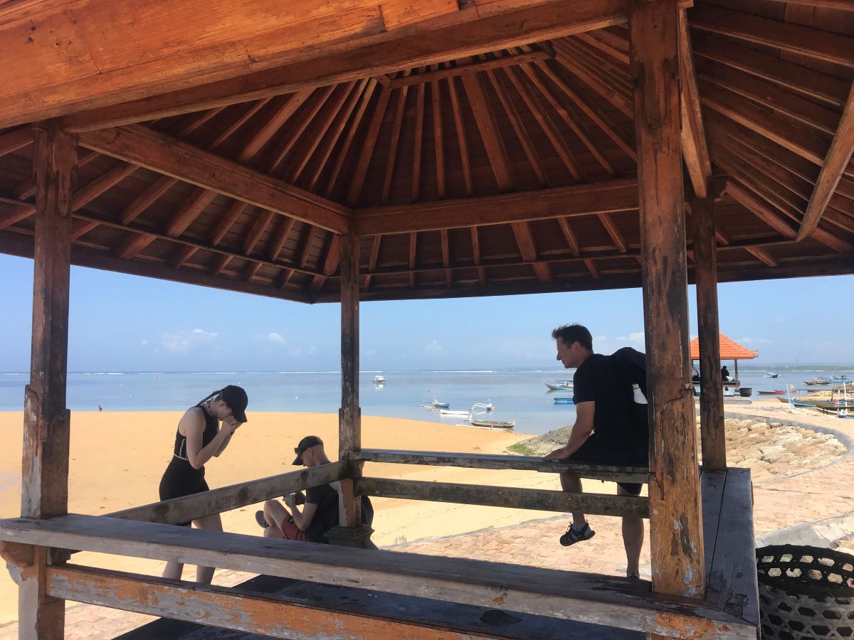 BOLONG: Dua wisatawan asing duduk di kayu bagian pinggir bale bengong yang tidak ada papan duduknya di pantai Semawang Sanur