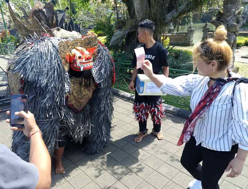 DAPAT SAWERAN : Pengamen ngelawang mendapat saweran dari wisatawan asing di Taman Ayun, Mengwi, Badung (adrian suwanto/radar bali).
