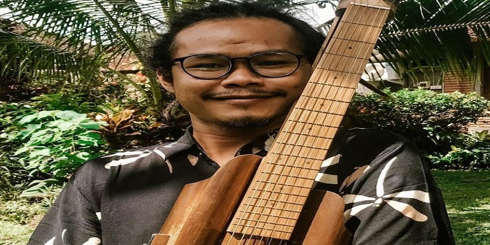 Rizal Hadi bersama alat musik bahan baku bambu ciptaannya.