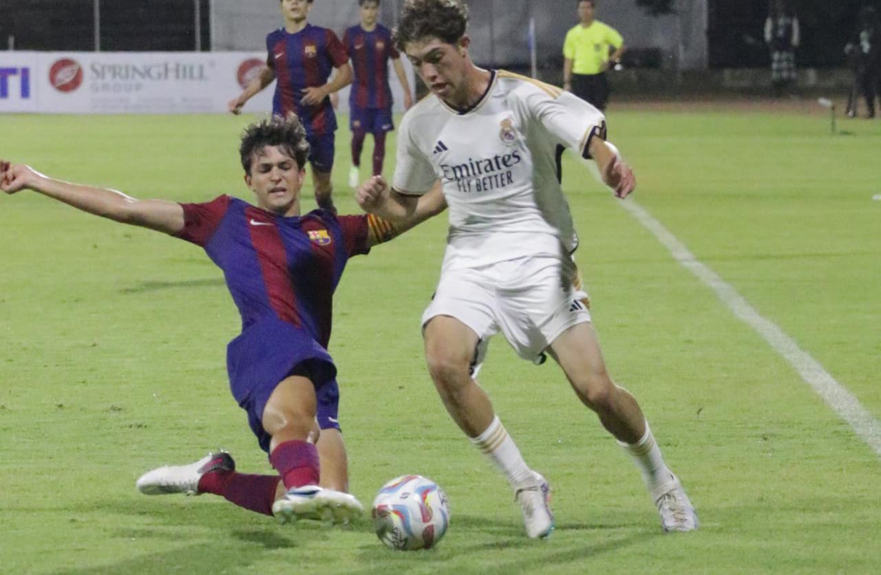 KETAT: Pemain Real Madri Junior (kanan) dihadang pemain Barcelona Junior di stadion Ngurah Rai Denpasar (11/8/2023). (Radar Bali Photo)
