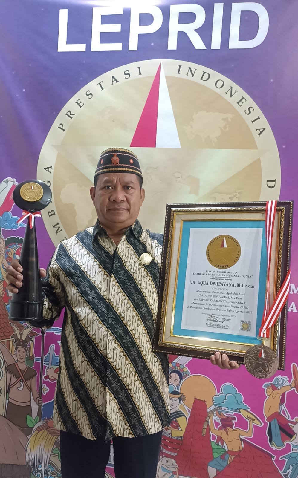 REKOR BARU: Ketua Umum Leprid Paulus Pangka menunjukkan piagam penghargaan, medali, dan piala untuk Dr Aqua Dwipayana. (RADAR BALI)