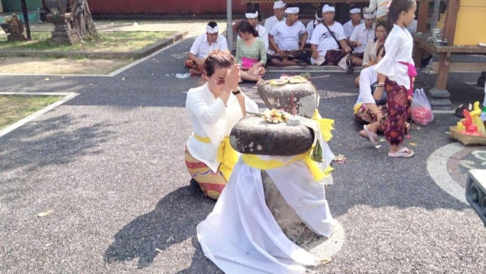 MEMELUK BATU: Pemedek memeluk batu kapong di Pura Gunung Baleku. Apabila berhasil memeluk batu, mereka yakin permohonannya akan terkabul