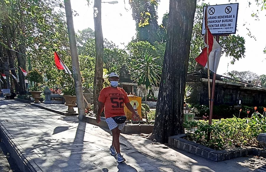 PERINGATAN: Sebuah papan pengumuman dipasang di lapangan Puputan Renon. Papan ancaman bagi pemasang jerat burung liar di alam bebas.