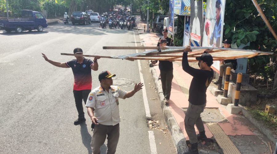 MERUSAK KEINDAHAN: Satpol PP Kota Denpasar tengah menurunkan baliho caleg dan parpol Kamis (7/9/2023)