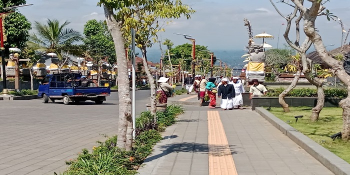 Salah seorang pedagang asongan menawarkan dagangannya kepada pemedek di kawasan pura Agung Besakih.