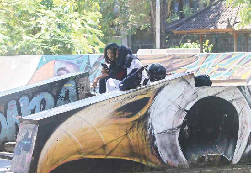 HEMAT KUOTA: Dua remaja memanfaatkan Wi-Fi gratis di Taman Lumintang Selatan (Skatepark). Di lokasi ini Wi-Fi bisa diakses.(miftahuddin m.halim)