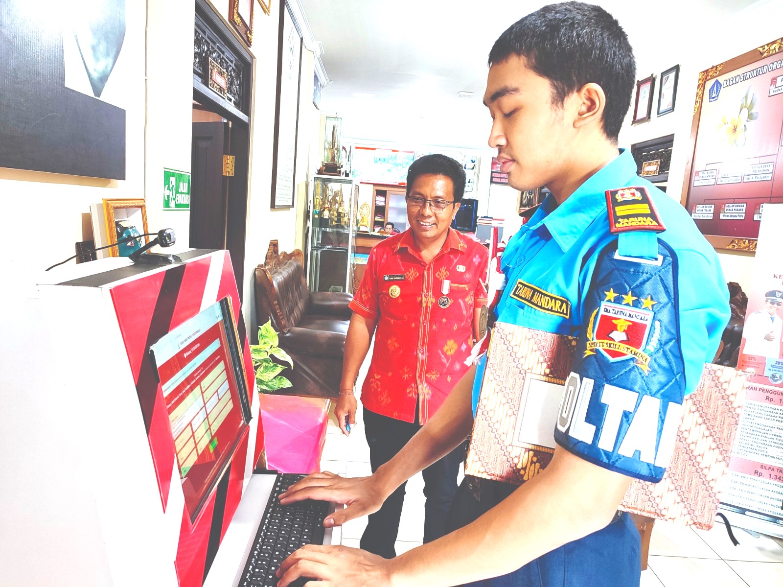 PANTAU RUTIN : Kadek Sukarma (kiri)memantau tamu sedang mengisi buku tamu digital. (maulana sandijaya)