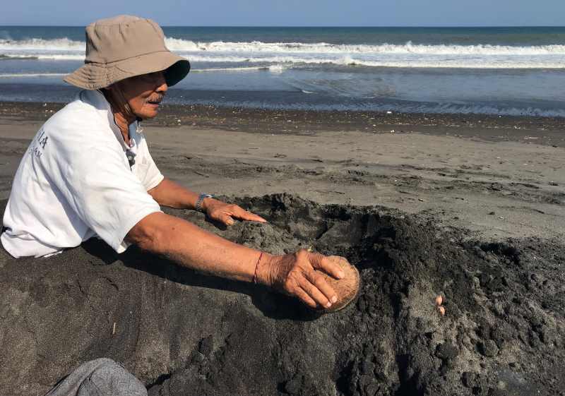 TERAPI : I Made Ririg menguruk sebagian badannya dengan pasir pantai, di Pantai Biaung, Kesiman, Denpasar. (miftahuddin m. halim)