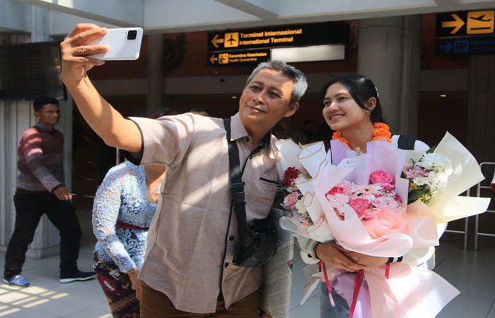 Desak Rita (kanan) saat diminta foto bersama, seusai  tiba di bandara ngurah rai.