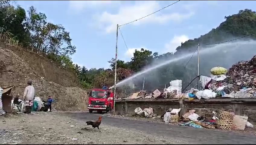 CEGAH KEBAKARAN: Tim pemadam kebakaran Kabupaten Klungkung terus menyempro gunungan sampah di TPA Sente agar tidak terbakar.