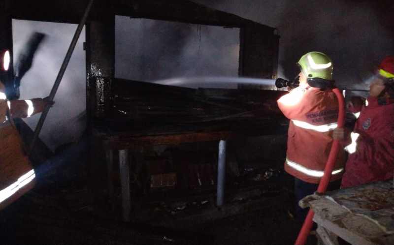 KERJA KERAS MATIKAN API: Petugas pemadam kebakaran bekerja keras memadamkan api yang melalap warung sembako.(Foto Dinas Dankartan Karangasem)