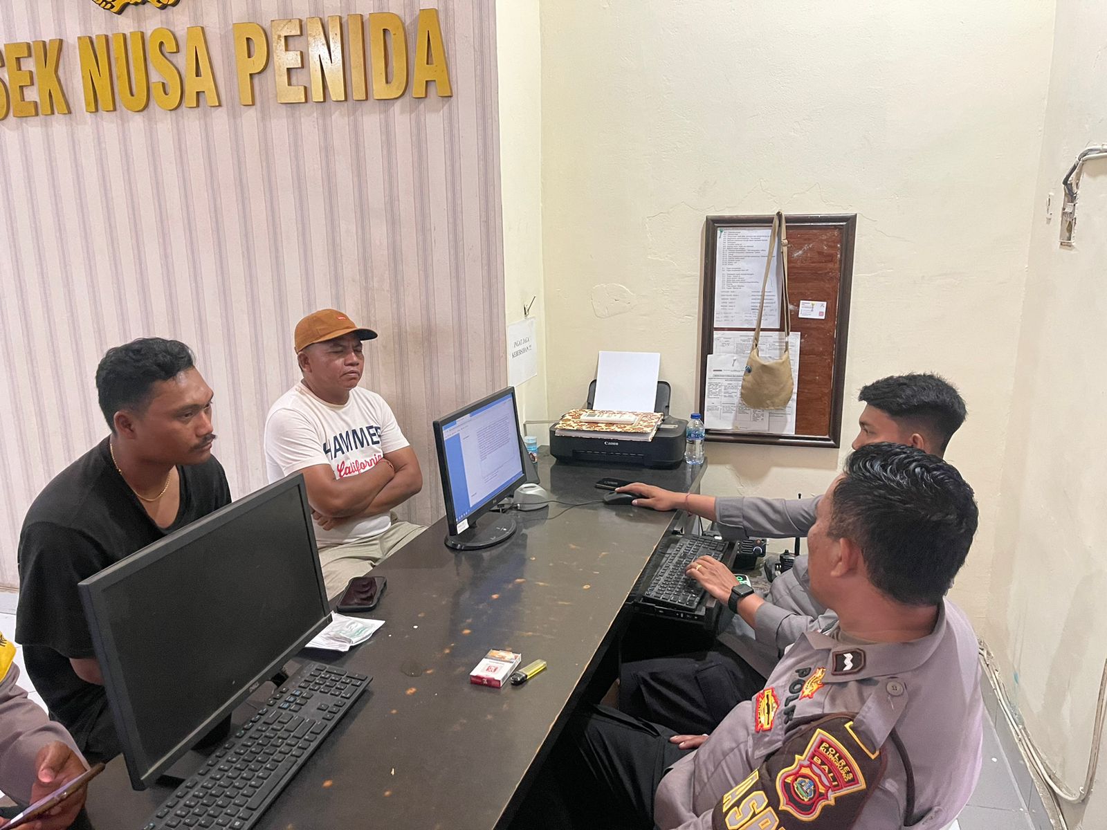 LAPORAN: Korban pemukulan oleh Pecalang Made Junnarthe (kaus hitam) saat melapor ke Polsek Nusa Penida  (29/10).