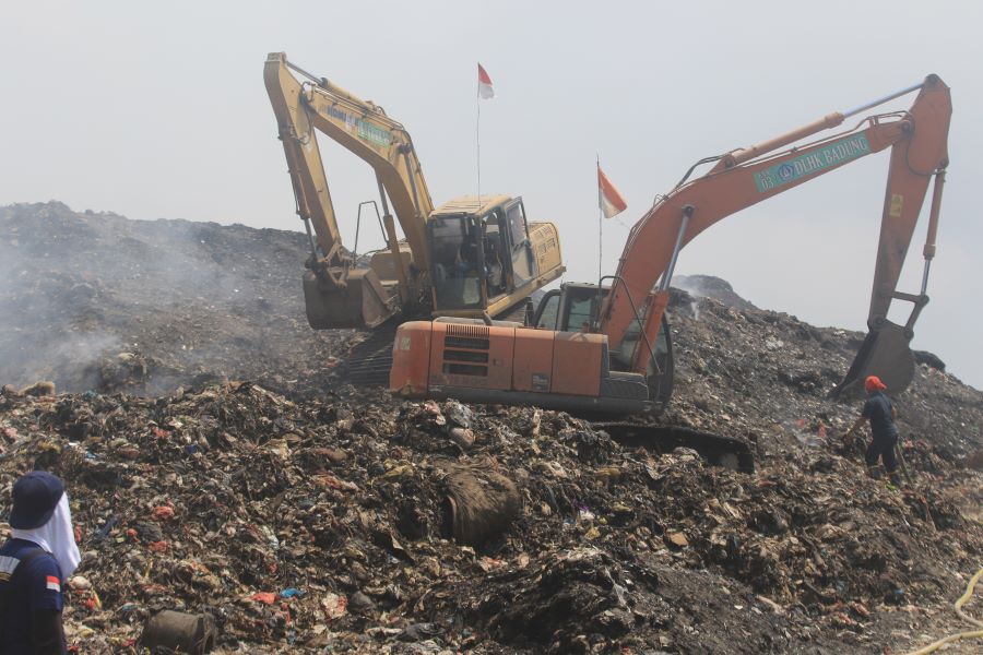 TERUS MEREDAM API: Sebuah alat berat terlihat membolak-balikkan sampah yang masih berpotensi menyimopan bara untuk meredam kebakaran di TPA Suwung.