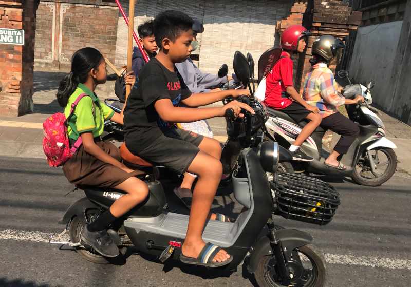 MELANGGAR ATURAN : Seorang bocah mengendarai sepeda listrik dengan berboncengan, melintas di Jalan Subita, Denpasar. (miftahuddin m. halim/radar bali)
