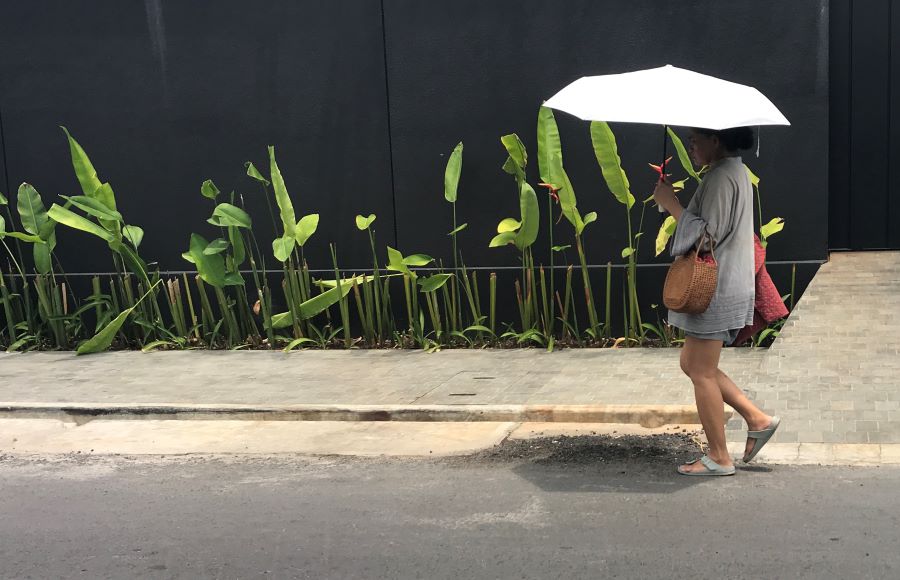 CUACA MENYENGAT: Pejalan kaki terlihat menggunakan Payung , saat hari yang terik melebihi biasanya, melintas di jalan Danau Tondano, Sanur, 1 November 2023.