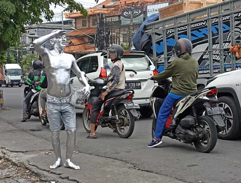 KERASNYA KEHIDUPAN : Manusia perak beraksi di jalanan Gatsu Barat-Jalan Pidada, Denpasar. (Foto :adrian suwanto/radar bali)