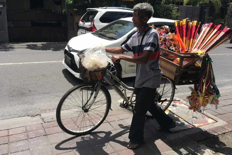 PEDAGANG MUSIMAN : Pedagang terompet tahun baru berkeliling di Jalan Raya Dalung, Kuta Utara, Sabtu (16/12/2023). (miftahuddin m.halim/radar bali)