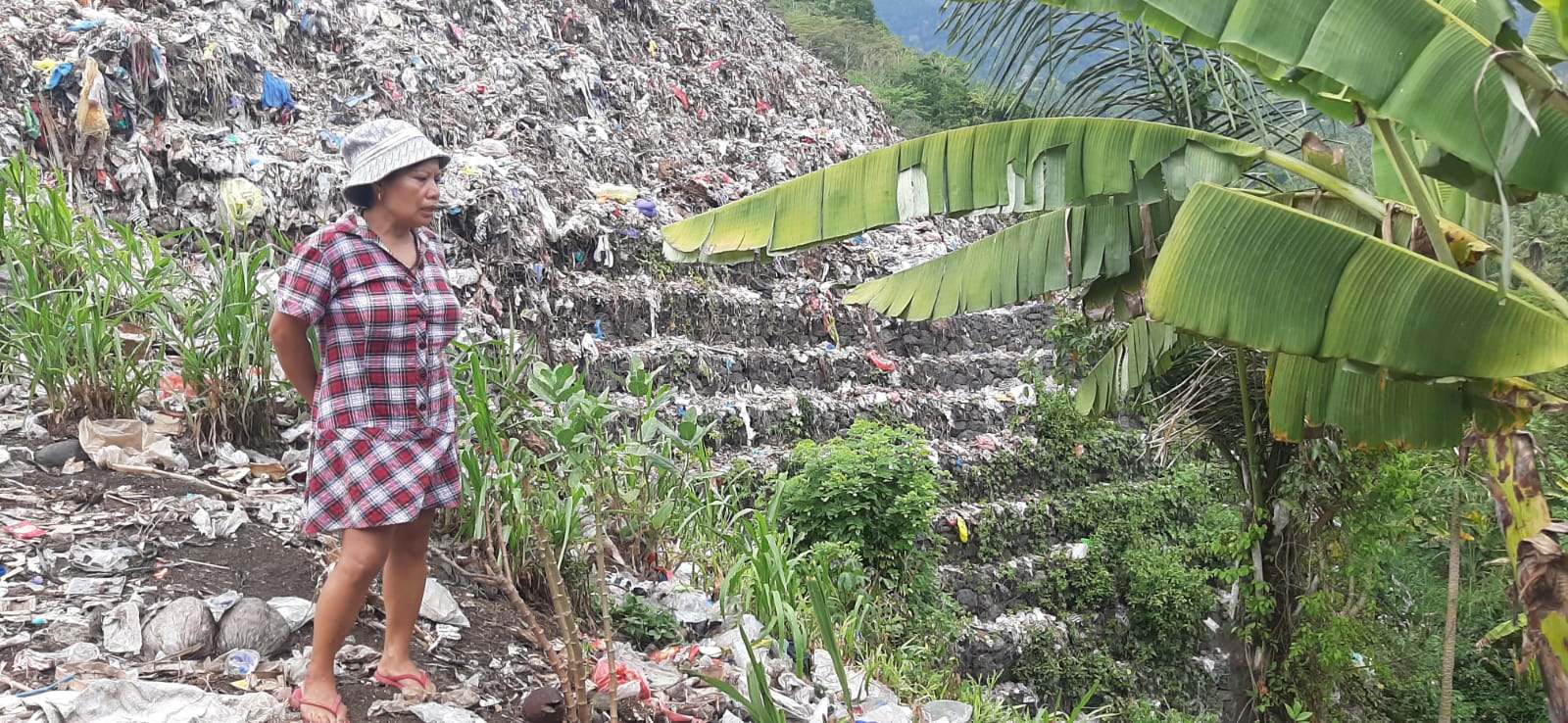 TUTUPI LAHAN: Seorang warga pemilik lahan di area TPA Sente Klungkung menunjukkan lahan pertaniannya diterjangan sampah mengakibatkan tanaman tak berkembang.