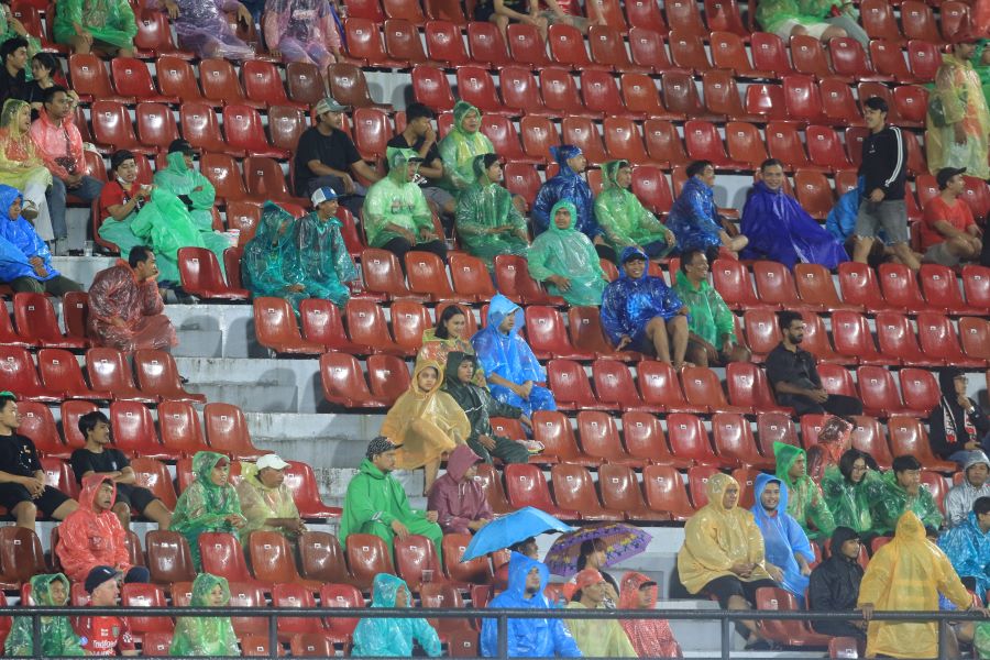 PAKAI MANTEL: Sejumlah suporter memakai mantel saat pertandingan berlangsung hujan di Stadion Kapten I Wayan Dipta Gianyar