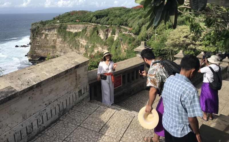 PUNYA SENSASI TERSENDIRI : Sejumlah pelancong asing berfoto di kawasan Pura Uluwatu. (miftahuddin/radar bali)