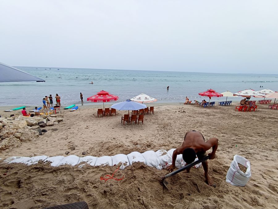 CEGAH ABRASI: Salah seorang pedagang di Pantai Kuta tengah memnbuat karung pasir untuk mencegah abrasi Pantai Kuta Badung Bali