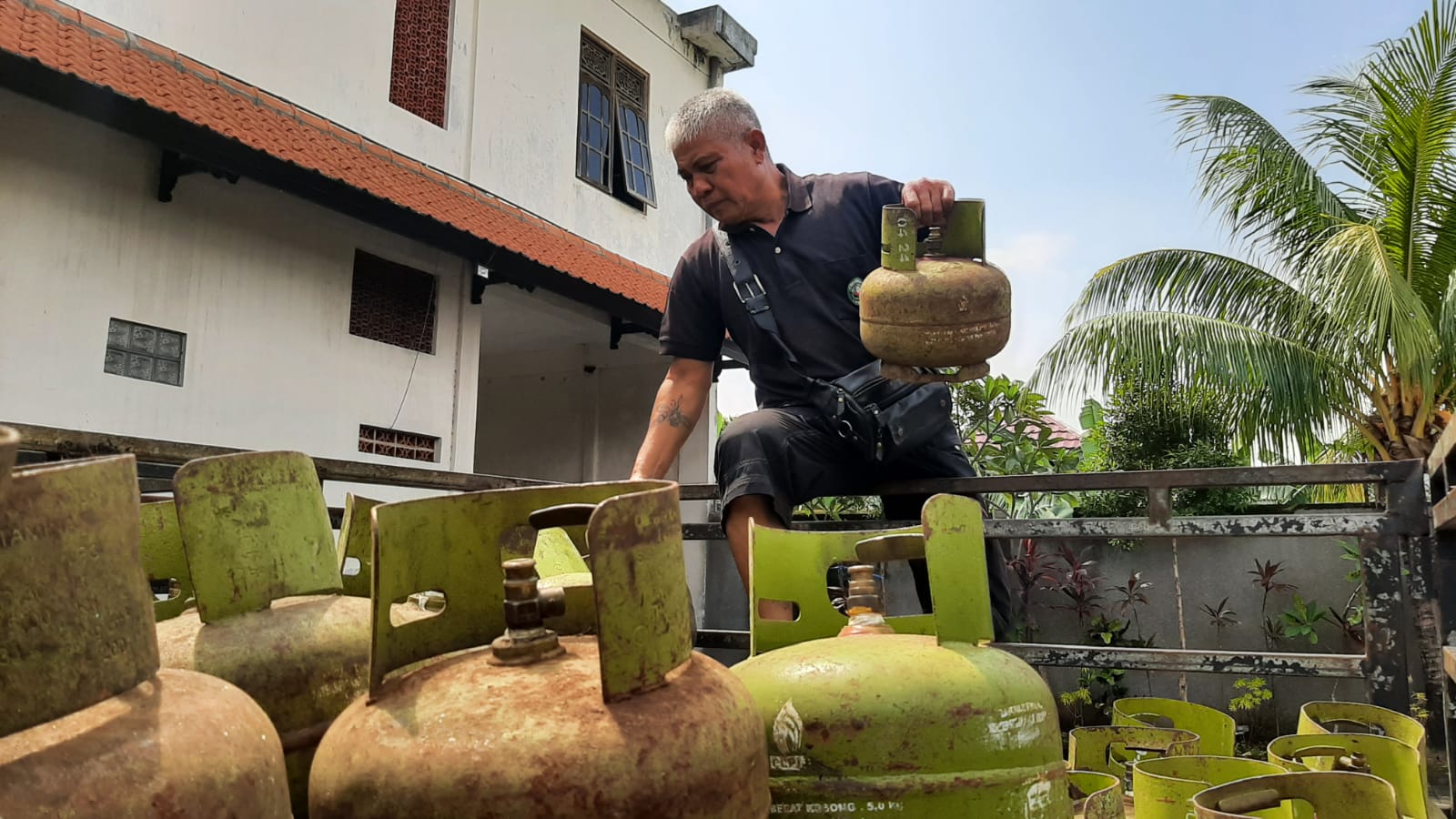 MASIH KURANG UNTUK KLUNGKUNG : Seorang agen gas elpiji di Klungkung tengah menaikkan gas elpiji tiga kilogram ke atas mobilnya (dewa ayu pitri arisanti/radar bali)