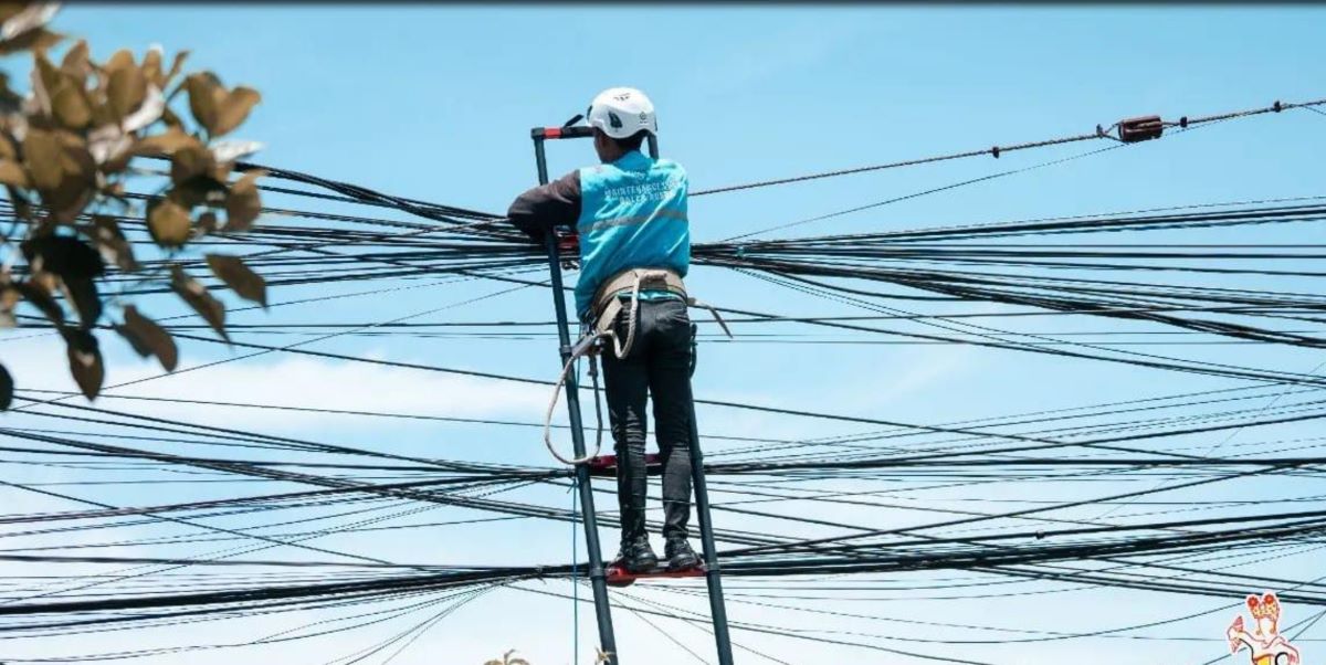 SUPAYA AMAN: Petugas sedang melakukan perbaikan kabel optik yang menjuntai di jalan Gunung Soputan Padangsambian Klod Denpasar