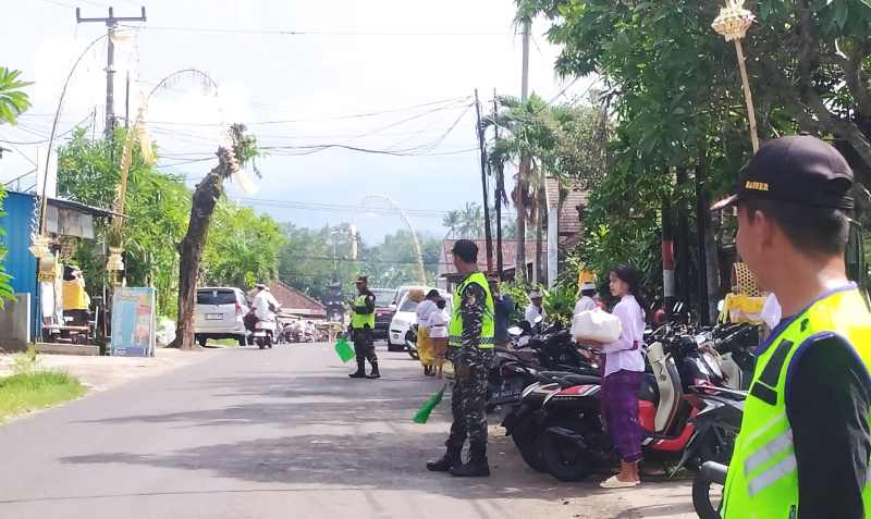 BERTOLERANSI DAN SALING MEMBANTU: Banser NU Ranting Banyubiru, mengatur lalu lintas jalan saat persembahyangan Galungan di Pura Puseh Banyubiru, Rabu (28/2/2024). (m.basir/radar bali)