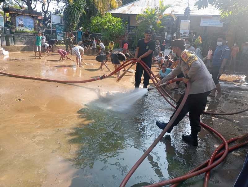DIBERSIHKAN: Suasana pembersihan lumpur bekas banjir di SDN 3 Bungkulan oleh guru, siswa, orang tua siswa, dibantu Damkar, BPBD Buleleng, juga Polsek dan Koramil Sawan.(francelino junior)