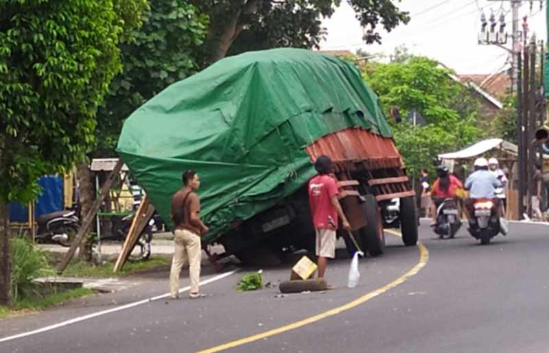 MENGAGETKAN : Truk berukuran cukup besar ini akhirnya miring di tikungan Jalan Denpasar - Gilimanuk, Banjar Pangkung Buluh, Desa Kaliakah, Jembrana. (m.basir/radar bali)