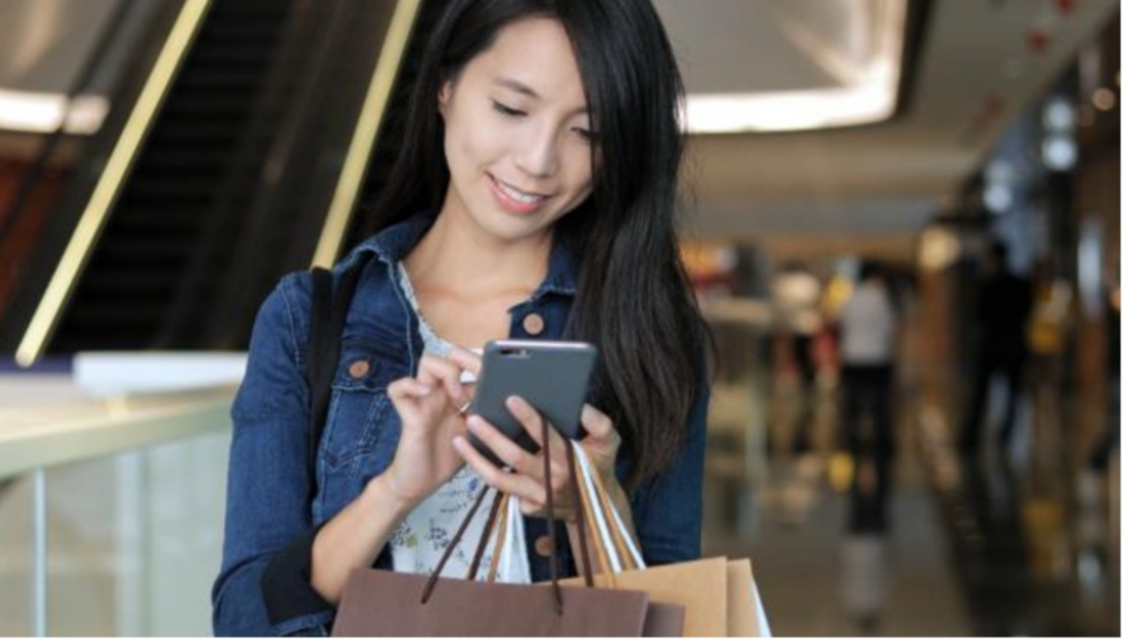 Sumber foto: https://elements.envato.com/shopping-woman-using-cellphone-and-holding-shoppin-UPBBMA8