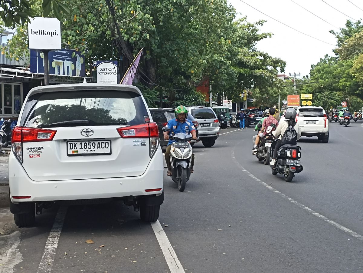 Banyak kendaraan roda empat parkir sembarangan di tepi jalan raya kawasan Renon Denpasar